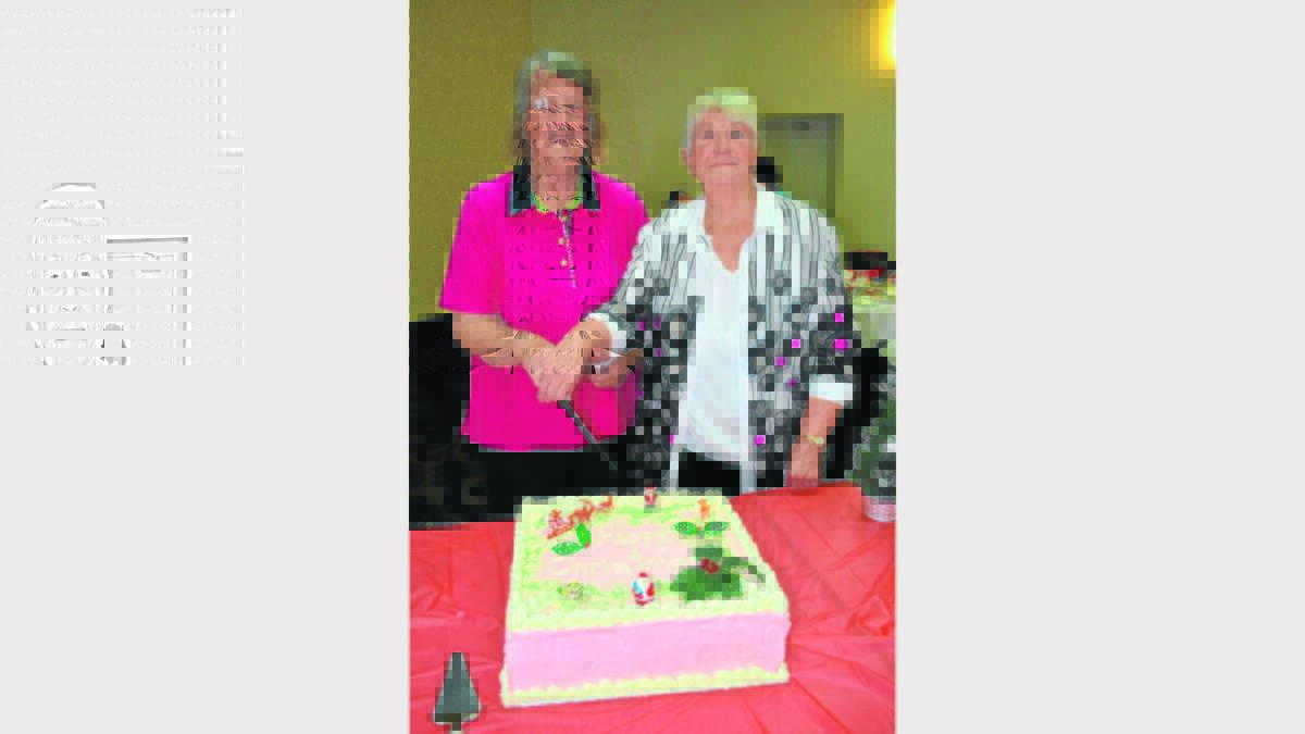 Committee members Jenny Glenn and Melva Cloake cut the cake at the Combined Pensioners and Superannuants Christmas luncheon at the Young Services Club recently.